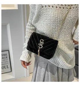 Close-up of black velvet crossbody bag with V-shaped quilting and gold tassel charm