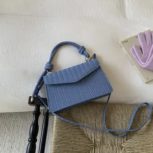 Light blue woven minimalist square handbag with top handle and crossbody strap