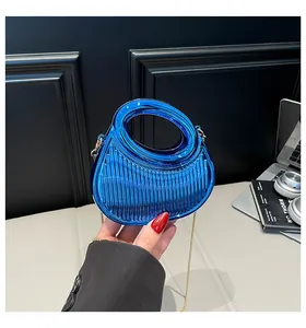 Détail de pochette en acrylique bleu à rayures verticales et chaîne dorée