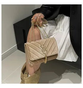 Detail of velvet cross body bag with gold V-quilt pattern and metal tassel charm