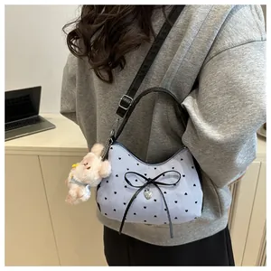 Détail du sac rayé bleu avec imprimé cœur, nœud et pendentif lapin en peluche doux