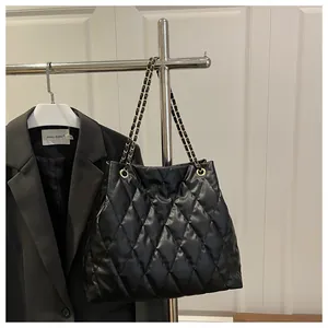 Detail of black quilted leather texture with gold metal chain on a stylish tote bag