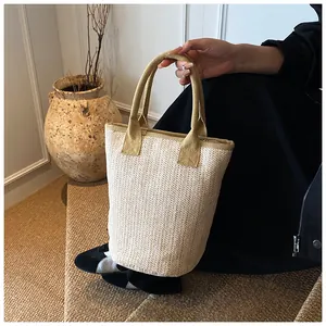 Detailed close-up of beige woven bucket bag featuring premium V-pattern and fabric handles