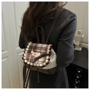 Détail d'un mini sac à dos à carreaux avec écusson cerise et nœud marron