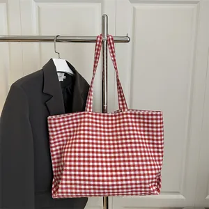 Red and white gingham canvas tote bag hanging on a rack for a casual minimalist summer look