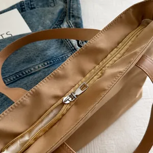 Détail de la fermeture éclair en métal et de la texture du tissu du grand sac beige