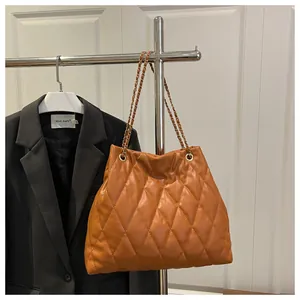 Close-up of quilted pattern and gold chain strap on a brown PU leather shoulder bag