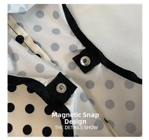 Detailed macro view showing the magnetic snap closure on the black polka dot tote bag