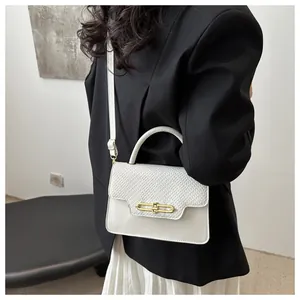 Detail of cream white leather handbag featuring woven texture flap and gold lock closure