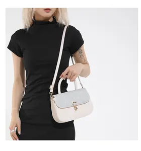 Sac à main élégant beige clair avec rabat pailleté argenté porté avec une robe noire