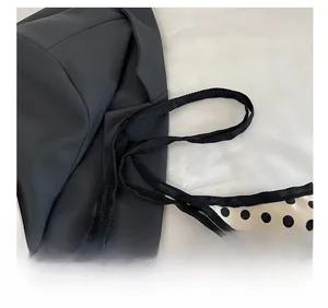 Detail showing the comfortable black shoulder strap and polka dot fabric stitching