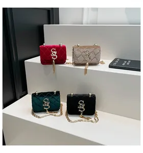 Vue détaillée de sacs bandoulière en velours avec détails dorés et pompons en 4 tons