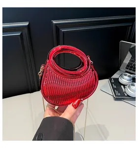 Détail du sac pochette rouge en acrylique avec surface texturée et chaîne dorée