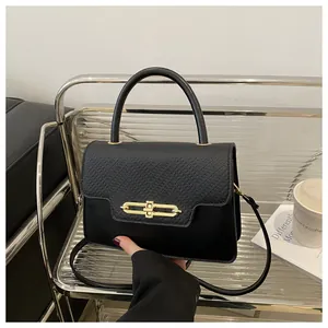 Detail of black leather handbag with litchi texture flap and gold metal clasp