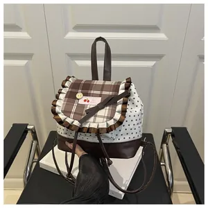 Détail du sac à dos à carreaux avec volants marron, écusson cerise et nœud