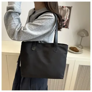 Close-up of the black nylon tote bag with leather straps in a cozy lifestyle setting
