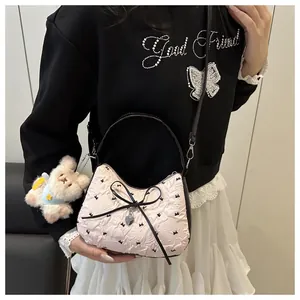 Détail du sac beige avec nœud noir et peluche d'ours porté par un mannequin