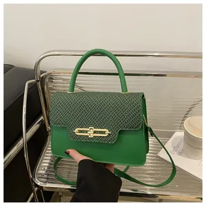Detail view of green handbag showing geometric woven texture and gold metal buckle closure
