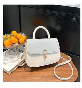 Détail d'un sac en cuir blanc avec paillettes argentées et fermoir en fer à cheval doré
