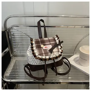 Détail d'un petit sac à dos avec motif cerise, rabat à carreaux et nœud décoratif