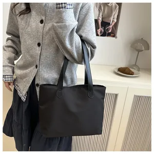 Close-up of minimalist black nylon tote bag shown in a modern home lifestyle setting