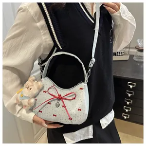 Détail du sac à bandoulière bleu clair avec nœuds rouges et un pendentif ours en peluche