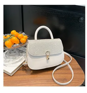 Détail d'un sac à main blanc avec rabat pailleté argenté et fermoir fer à cheval doré