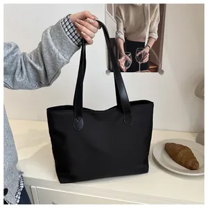 Large black nylon tote bag shown in a lifestyle setting for commuting and travel use