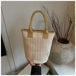 Detailed macro view of woven straw bucket bag with mustard yellow canvas strap handles