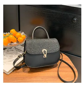 Détail du sac selle noir avec rabat pailleté et boucle fer à cheval dorée élégante