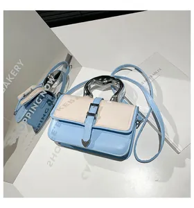Detail of blue and white leather crossbody bag with silver fluid metal handle and heart clasp