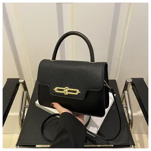 Close-up of black leather handbag featuring lychee texture and gold rectangular lock