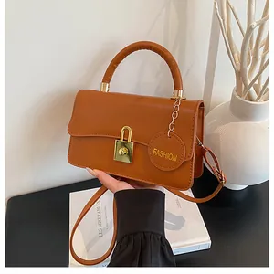 Detailansicht der braunen PU-Lederhandtasche mit goldenem Schloss und Mode-Anhänger
