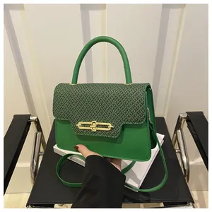 Detail of green leather handbag featuring textured flap and gold chain lock closure