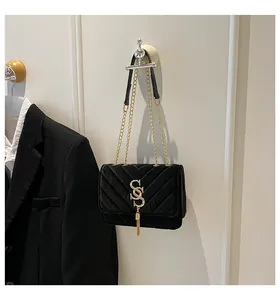 Détail du sac noir élégant à matelassage en V avec logo SS doré et bandoulière chaîne