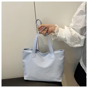 Close-up of light blue nylon tote bag with reinforced handles and smooth glossy finish