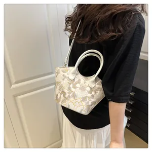 Detailed view of a white crossbody bag with yellow floral embroidery worn by a model