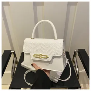 Detail of white handbag featuring snakeskin embossed flap and gold chain lock clasp