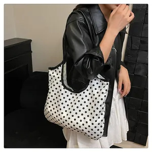 Modern black and white polka dot tote bag on shoulder for casual and stylish look
