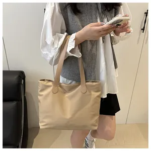 Beige high-density nylon tote bag with slim handles shown in a modern living room