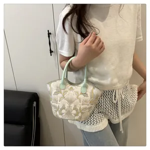 Detailed shot of vintage floral embroidery on a minimalist women's canvas shoulder bag