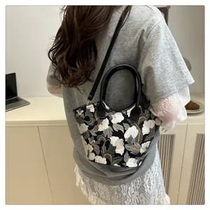 Detail of a black floral jacquard mini crossbody bag with leather handles shown on model