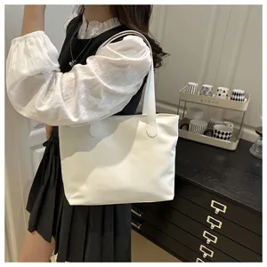 Detailed view of white minimalist tote bag showing smooth faux leather and dual shoulder straps