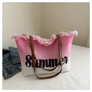 Detail of pink gradient beach tote bag featuring fringe trim and Summer text print
