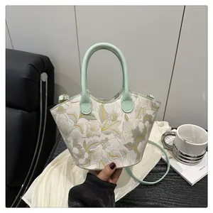 Detailed view of mint green hand-held tote bag with floral embroidery on white fabric