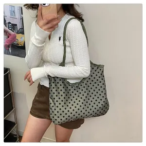 Lifestyle view of a large green tote bag with black polka dots worn on shoulder