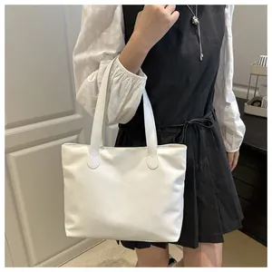 Detail showing white nylon tote bag hanging on shoulder with reinforced stitching