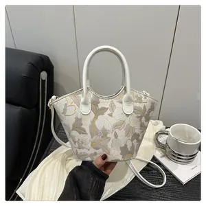 Detail of elegant white crossbody bag with floral embroidery and circular ring handle