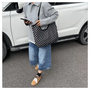 Outdoor lifestyle view of a large black tote bag with white polka dots on a model