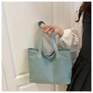 Handheld view of light green nylon tote bag featuring lightweight waterproof material